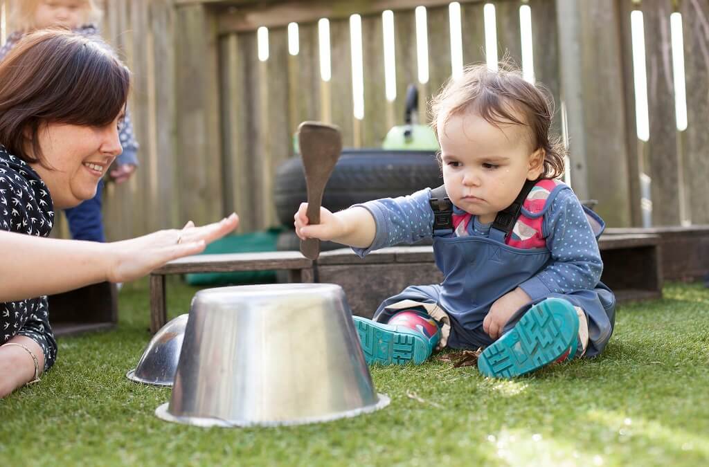 Child banging pot with stick
